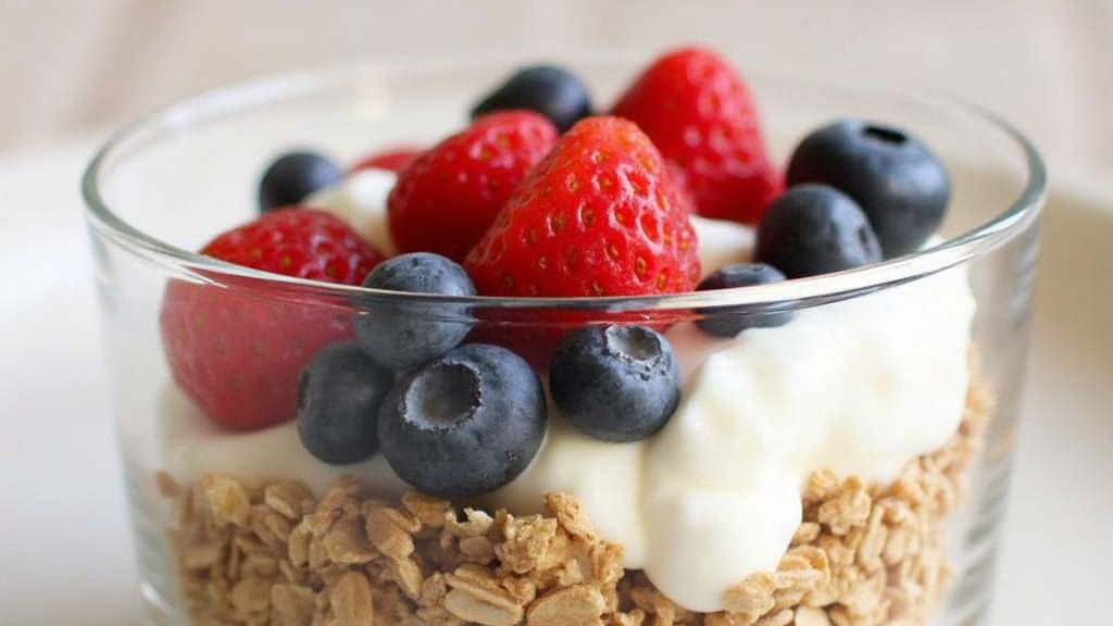 A layered Greek yogurt parfait with granola, berries, and a drizzle of honey.